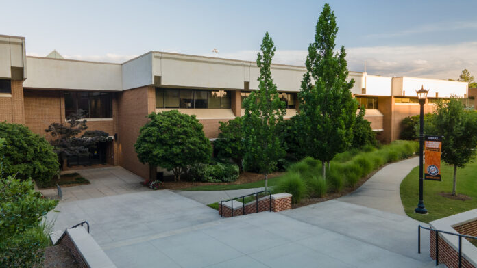 Exterior of the School of Medicine, a two story brick building with a flat room and landscaping.