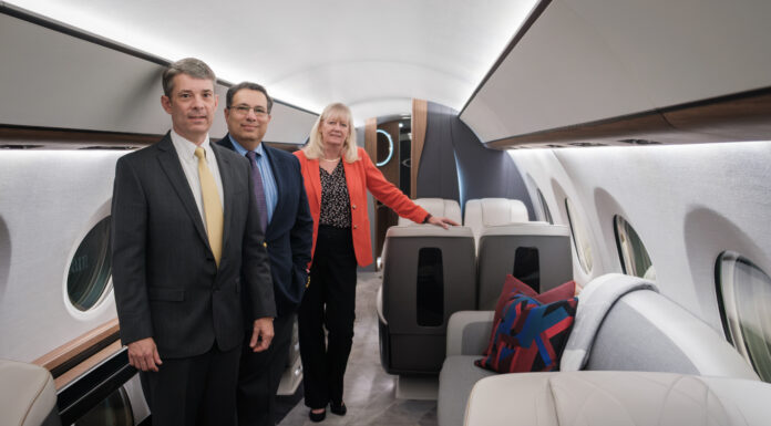Mercerians lead engineering work at Gulfstream Aerospace Three people in business attire stand inside a business aircraft with gray seats and walls.