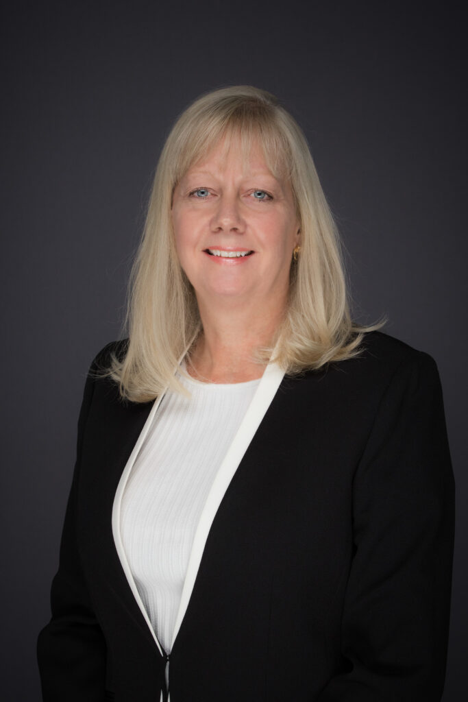 A headshot of a woman wearing a white blouse and a black blazer.