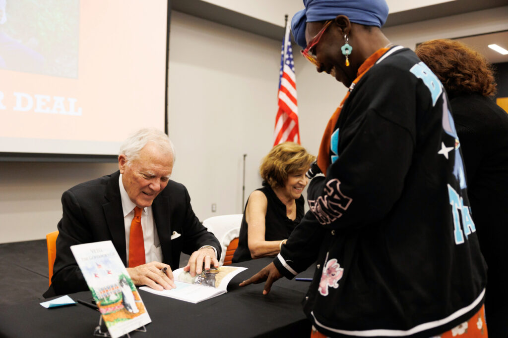 Former Georgia Gov. Nathan Deal signs a book for a visitor at a public event.