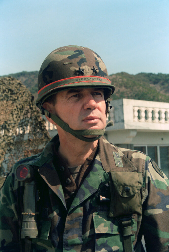 A man is pictured from the waist up wearing military fatigues. His helmet says "Kicklighter."