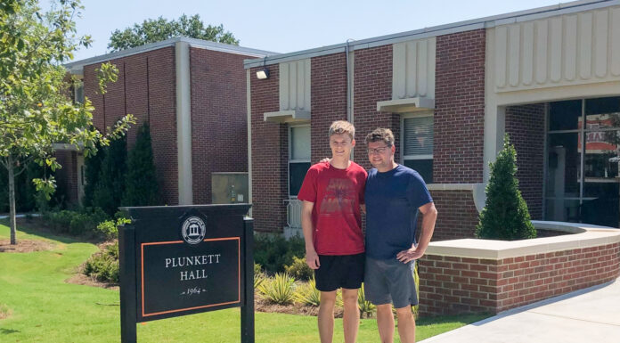 Dad gets blast from the past when he moves son into his former Mercer residence hall Father and son stand outside in front of a 1960s style, brick building and next to a black sign that says Plunkett Hall.