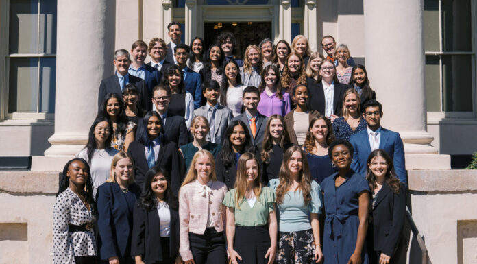 Mercer welcomes 13th class of Stamps Scholars Group of approximately 50 people standing on the steps of a building with large columns and shuttered windows. Most individuals are dressed in formal or business attire. They are arranged in rows, smiling at the camera. The background includes the entrance of the building with a decorative arch above the doorway.
