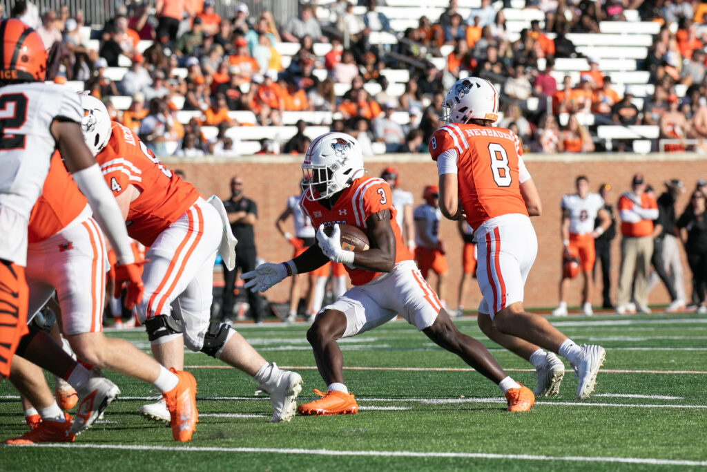 A college football game in action with players from teams identified by their jerseys as Princeton and Mercer. Mercer's Dwayne McGee, wearing jersey number 3, is carrying the ball.