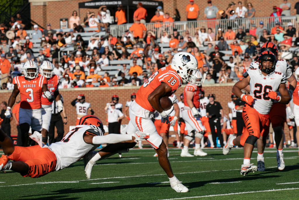 Mercer's Adjatay Dabbs, wearing a jersey with number 18, runs with the ball during a college football game against Princeton.