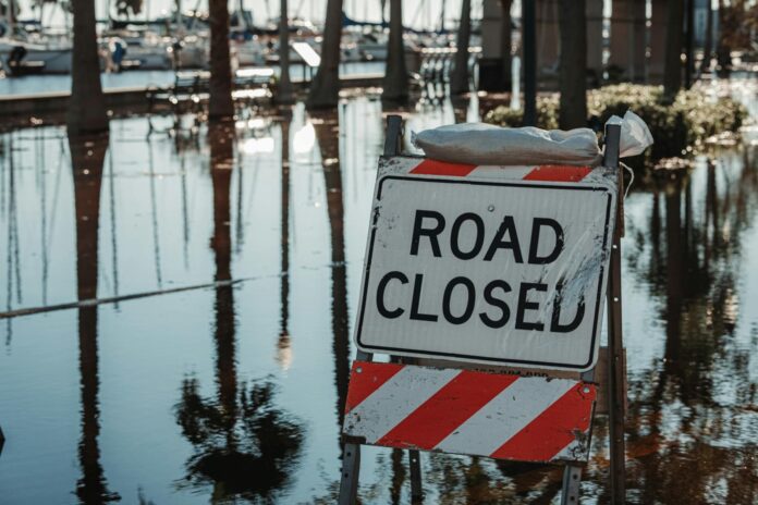 A sign that reads, "Road Closed" sits in water.