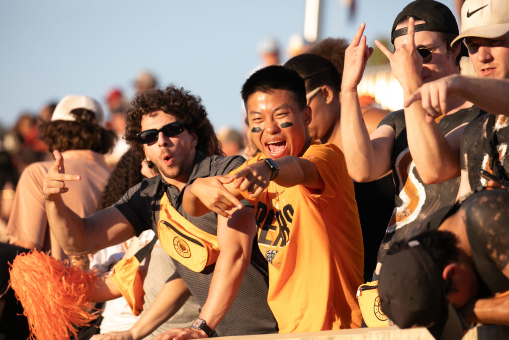 Enthusiastic fans clad in Mercer Bears gear cheer and point during a sunny outdoor event.