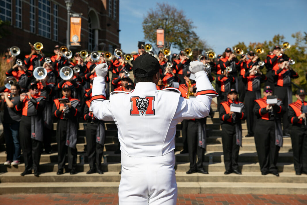 A drum major leads the Mercer marching band during a performance on outdoor steps.