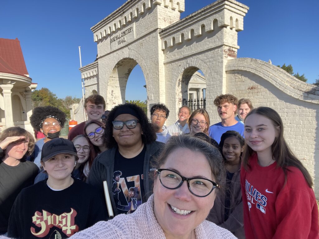 A group of people smiles for a photo in front of an arched brick entrance gate.