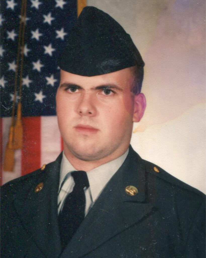 A young Garland Crawford wearing a navy blue military uniform. A flag is behind him. 