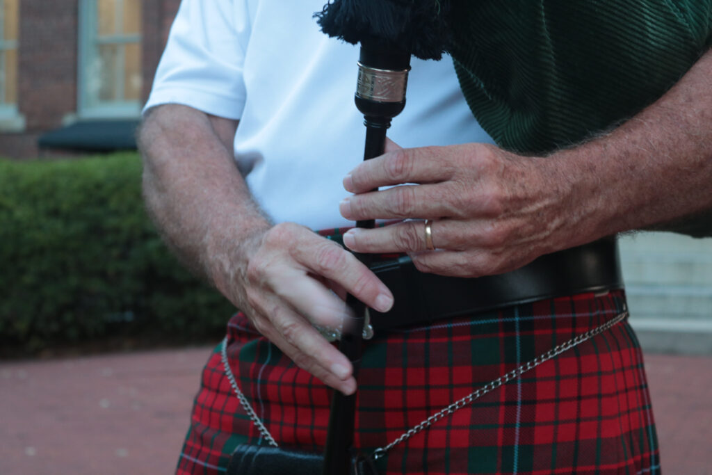 Close-up of a person in a traditional Scottish kilt holding bagpipes.