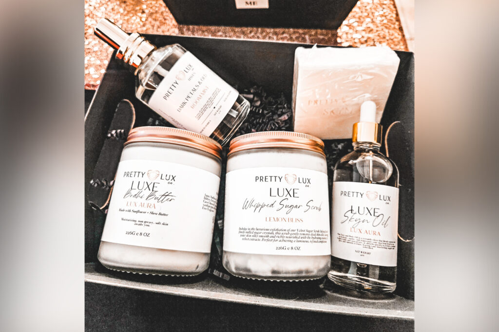 A gift box containing body butter, sugar scrub, skin oil, bath soap and room mist, all labeled Pretty Luxe Co.