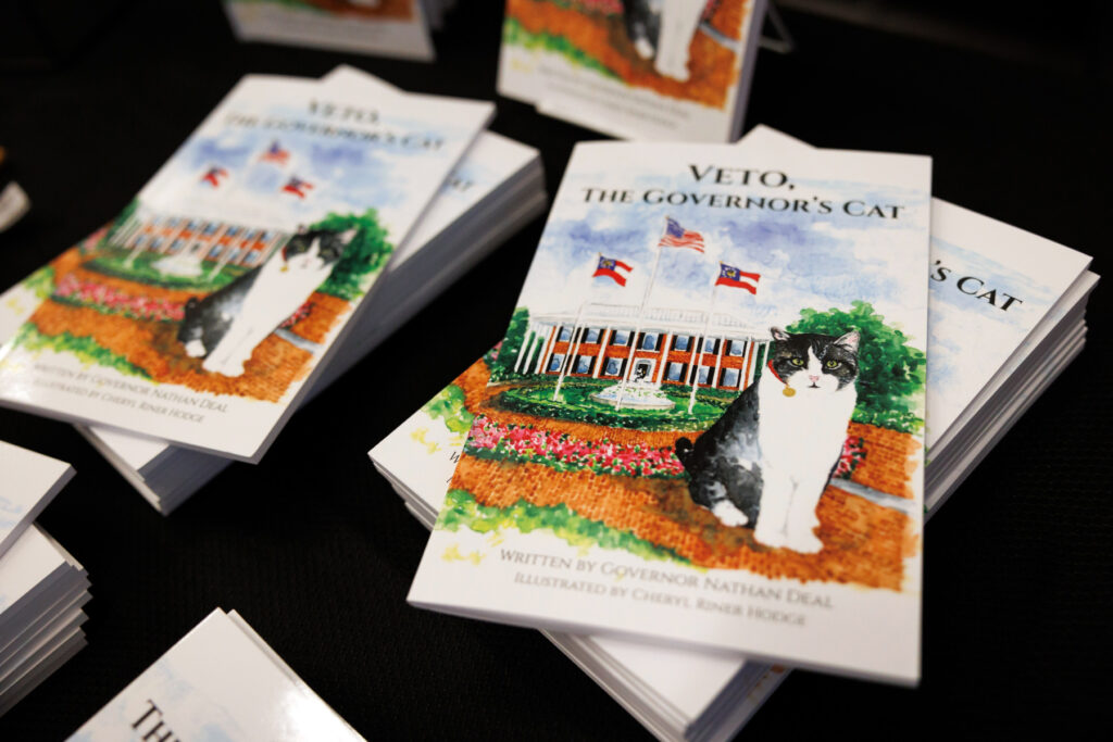 Several copies of the book "Veto, the Governors Cat" featuring a cat and the governor's mansion on the cover.