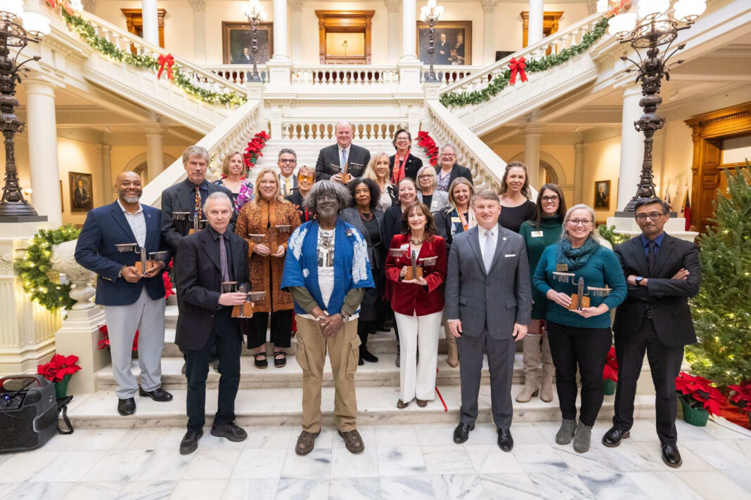 A group of people posing on a staircase in a decorated building, holding awards.