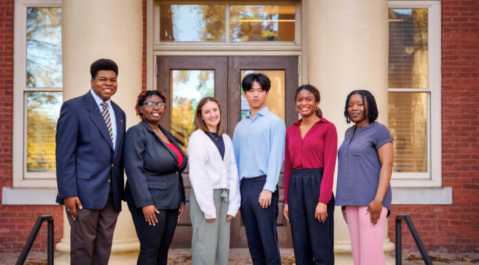 Eleven students selected to study abroad as Gilman Scholars A group of six people stands in front of a building with columns, dressed in business casual attire, facing the camera.
