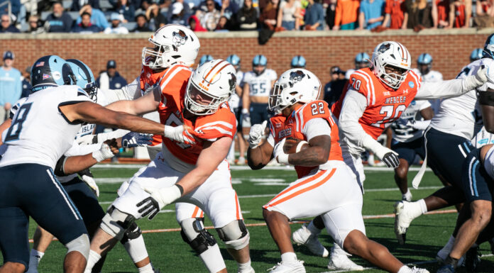 Mercer football to make national broadcast TV debut during FCS quarterfinal A college football game between Mercer and Rhode Island with Mercer players blocking and running while Rhode Island players attempt to tackle.