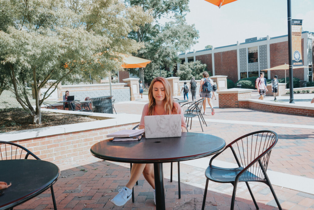 Mercer student sitting at an outdoor table at Cruz Plaza.