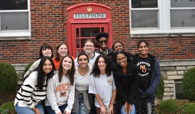 Mercer debaters take top awards at Missouri tournament A group of people smile in front of a red telephone booth against a brick building.