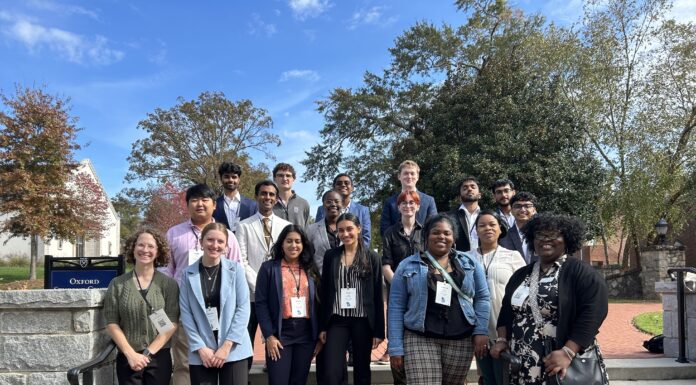 Mercer freshman awarded best presentation at the Georgia Undergraduate Research Conference A diverse group of people stands on outdoor steps, smiling, with trees and a brick path in the background.