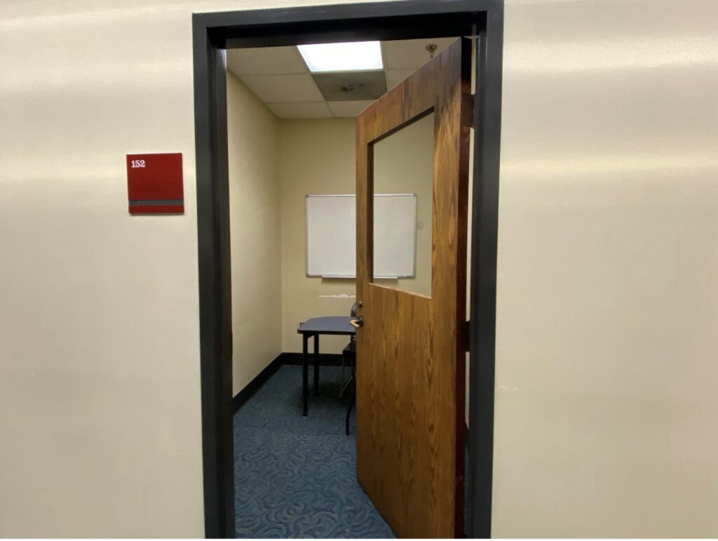 Open door to a study room with a table and whiteboard.