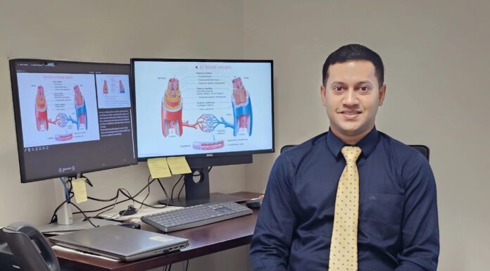 Mercer pharmacy researcher wins $2.98 million NIH grant to study new blood pressure benefits of statins Dr. Raquib Hasan in a blue shirt and yellow tie sits at a desk with two monitors displaying medical diagrams and articles.