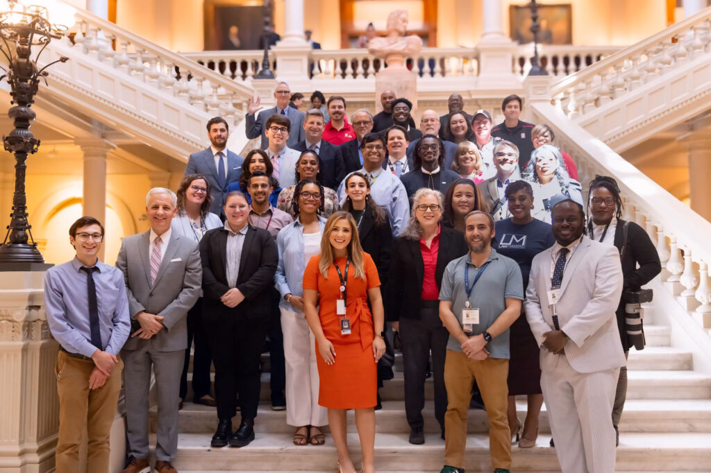 A diverse group of people posing for a photo on a grand staircase in the Georgia Capitol.