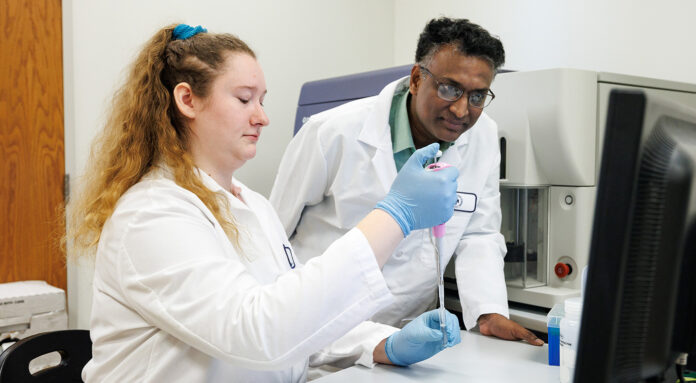 Two scientists in lab coats work together in a laboratory.