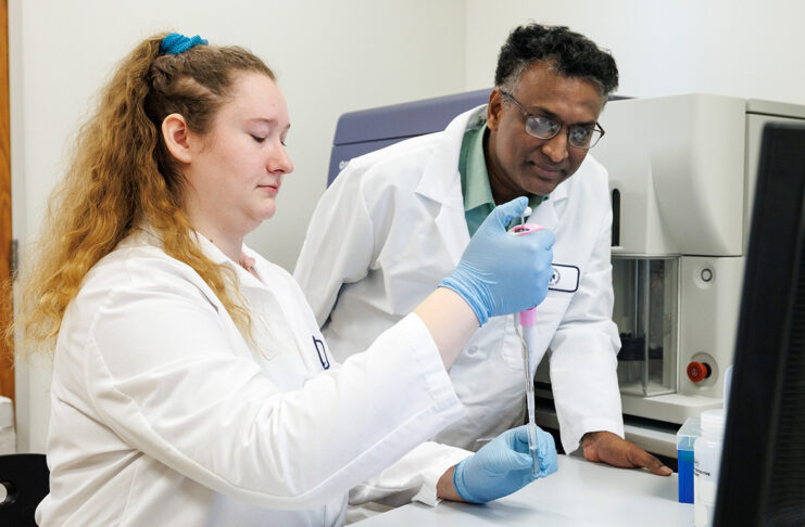 Two scientists in lab coats work together in a laboratory.