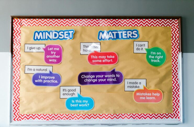 A bulletin board titled Mindset Matters features various colorful speech bubbles with motivational phrases in a classroom setting.