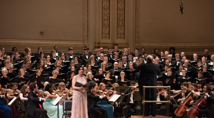 Mercer music students, faculty and alumni to perform at Carnegie Hall An orchestra and choir perform on stage, with a soloist standing in front of the musicians and conductor.