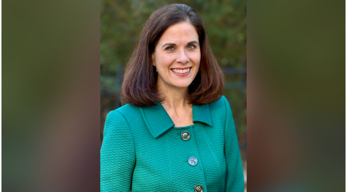 Dr. Lisa Murphey Lundquist named senior vice provost Woman with brown hair smiling, wearing a green textured jacket, standing outside with greenery in the background.