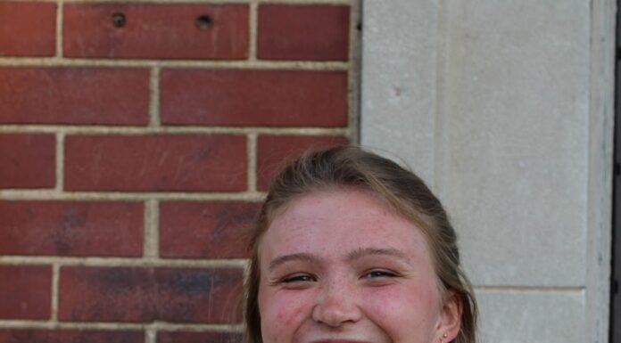 Senior develops earth science learning curriculum for Museum of Arts and Sciences Person smiling, standing in front of a brick and stone wall, wearing a floral dress.