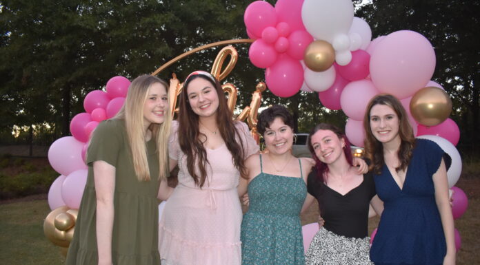Grad finds real-world experience, community at Mercer Five people smiling in front of a pink and white balloon arch outdoors.
