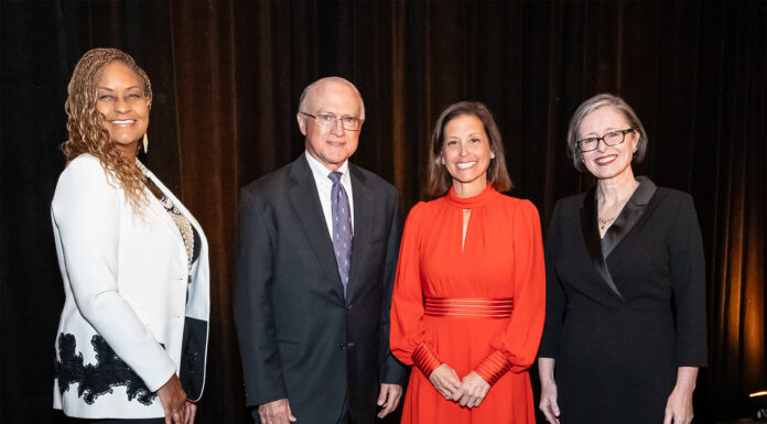 Mercer School of Law presents 2025 alumni awards Four people standing side by side in formal attire against a dark curtain backdrop.