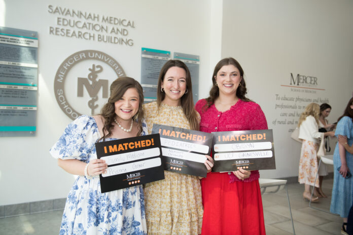 Three people holding I Matched! signs in a medical university building.