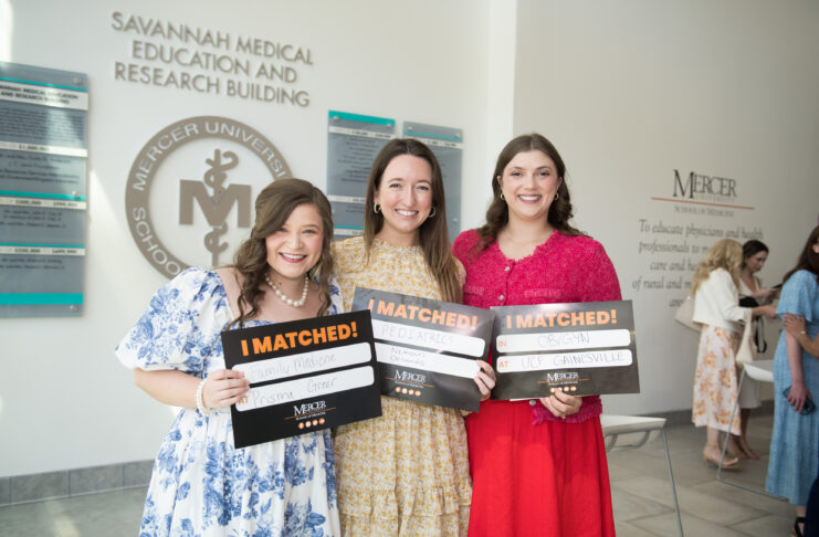 Three people holding I Matched! signs in a medical university building.