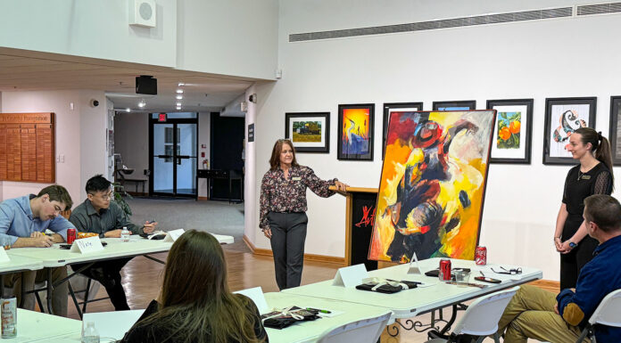 Innovative program teaches Mercer medical students empathy through art People in a classroom setting discuss a large abstract painting.