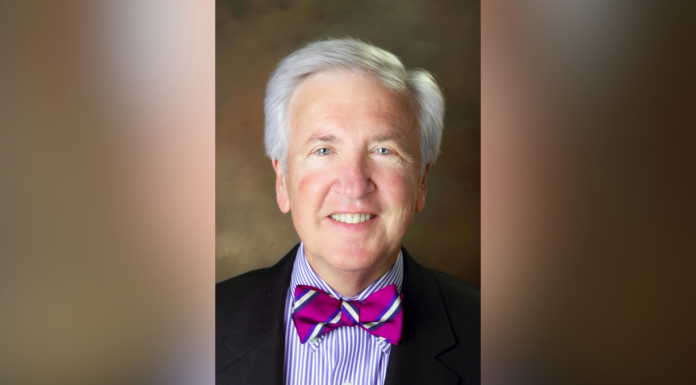 Executive VP for Administration and Finance Dr. James S. Netherton announces retirement A person with gray hair wearing a suit, colorful striped shirt, and bright purple bow tie, smiling at the camera.