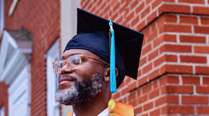 Graduate Spotlight: Ladji Ruffin Ladji Ruffin, in graduation attire, stands in front of a brick building, wearing an orange stole and a mortarboard.