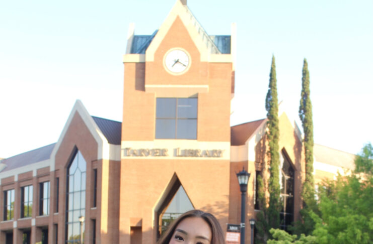 Linda Phan, in cap and gown stands, on Cruz Plaza.