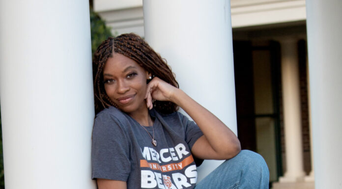 Graduate Spotlight: Quinecia Styles Smith Quinecia Styles Smith in a Mercer University Bears shirt and jeans sits on a stone ledge in front of white columns.