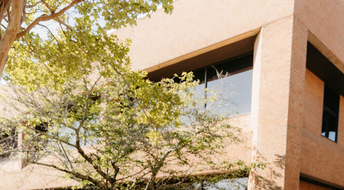 Graduate Spotlight: Rose Gambrell Rose Gambrell in a white dress and orange stole stands by Mercer's engineering building sign.