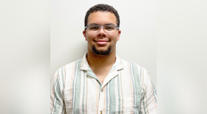 Mercer freshman awarded placement in competitive health professions program A man wearing glasses and a striped short-sleeve shirt stands against a plain white background, looking at the camera.