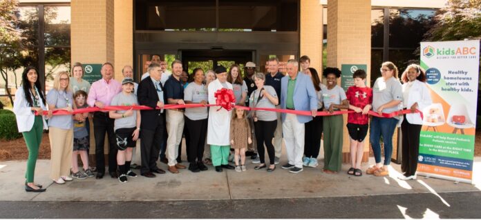 Upson ED ribbon cutting A group of people participate in a ribbon-cutting ceremony outside a building, with a kidsABC banner on the right side.