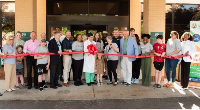 KidsABC celebrates Upson Regional Medical Center emergency department as part of Pediatric Emergency Care Project A group of people participate in a ribbon-cutting ceremony outside a building, with a kidsABC banner on the right side.