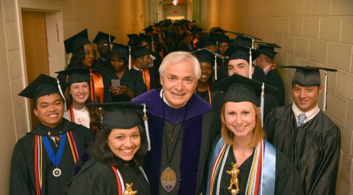 President Underwood announces plans to return to full-time teaching in the law school Graduates in caps and gowns stand in a hallway with a faculty member, holding awards and smiling at the camera.