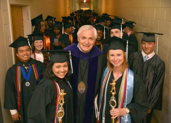 President Underwood pauses for a picture with students in the University Center before the 2015 Macon commencement. Photo by Stephen Saldivia Jones Graduates in caps and gowns stand in a hallway with a faculty member, holding awards and smiling at the camera.