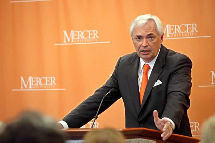 Mercer President William D. Underwood speaks at a podium in front of an orange Mercer University backdrop.