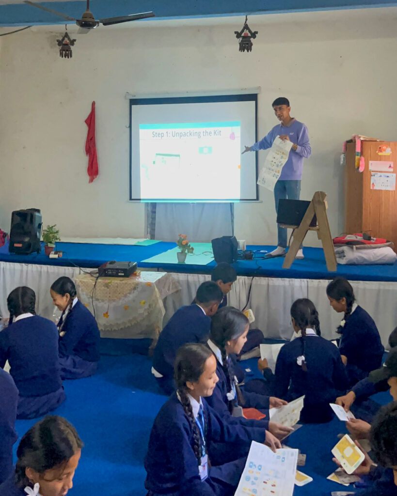 Rajwol Chapagain gives a presentation to a group of students seated on the floor.