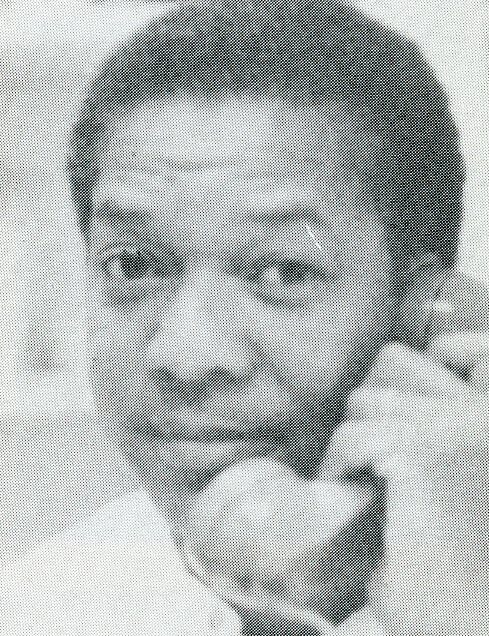 Black and white photo of a person holding a telephone receiver to their ear, looking directly at the camera.